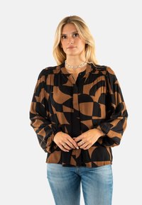 Blusa de manga larga con estampado marrón y negro, cuello redondo y puños fruncidos. La tela parece ligera y fluida.