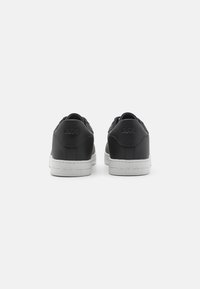 Black leather sneakers with white rubber soles. Features embossed logo on the heel and a smooth finish with minimal design accents.