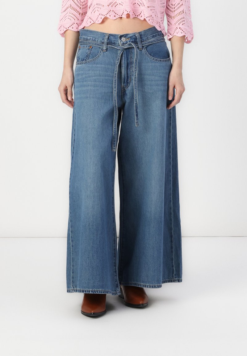 Light blue wide-leg jeans featuring a high waist, tie front, and straight-cut legs. The fabric has a soft texture with minimal distressing.