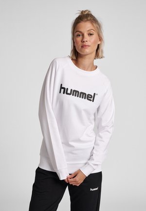 White sweatshirt with long sleeves and a crew neckline, featuring a large black "hummel" logo across the front. Soft texture, casual fit.