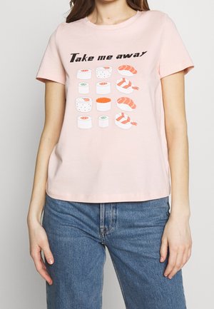 Frau trägt ein blassrosa T-Shirt mit Sushi-Illustrationen und dem Text "Take me away" darüber, kombiniert mit blauen Jeans.