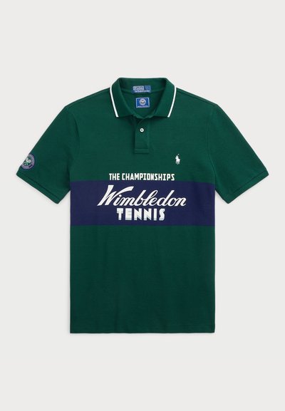Zelena polo majica z belim ovratnikom, ki ima osrednji mornarsko modri trak z napisom "Wimbledon TENIS" in majhno logo na rokavu. Iz bombažnega materiala.