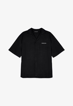 Juodas trumpas rankovėmis marškinėliai su laisvu siluetu, mygtukų užsegimu ir baltu „PEGADOR“ logotipu kairėje krūtinės pusėje. Lygus audinio paviršius.