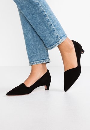 Czarne zamszowe szpilki z wąskim noskiem oraz niskim obcasem typu block heel, o gładkiej fakturze i minimalistycznym designie, zestawione z jasnoniebieskimi dżinsami.