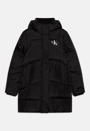 Manteau d'hiver noir matelassé avec capuche, poches avant et logo Calvin Klein Jeans sur la poitrine gauche, présenté sur un fond uni.