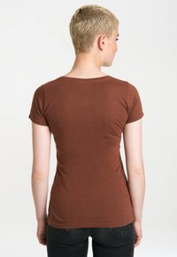 Brown short-sleeve t-shirt made of soft cotton with a fitted shape and a crew neckline, paired with dark jeans.