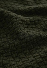 Dark green textured fabric with a woven pattern, displaying a soft, plush surface and slight variations in shade across the material.