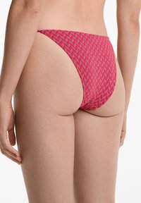 Slip bikini fucsia con un design alto, caratterizzato da forme geometriche e materiale texturizzato. Copertura minimale, con arricciature laterali.