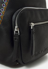 Schwarzer Leder-Rucksack mit silbernen Reißverschlüssen, ausgestattet mit einem aufwändigen mehrfarbigen Stickmuster und einer Vorderentasche mit Reißverschluss.