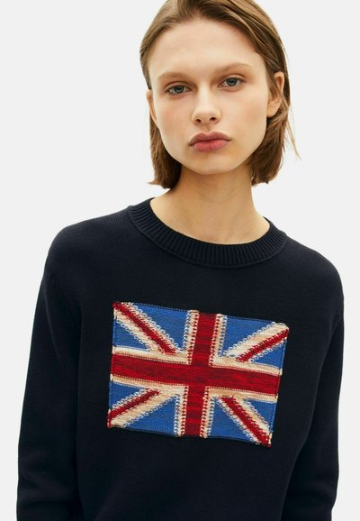 Jersey de punto azul marino con un diseño del Union Jack bordado en rojo, blanco y azul. Cuello redondo con textura acanalada.