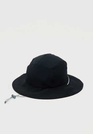 Chapeau bob noir avec large bord et sangle de menton ajustable sur un fond blanc uni.
