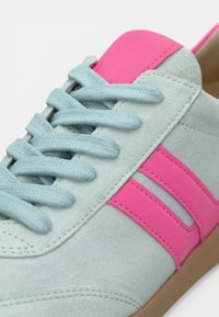 Αθλητικό παπούτσι με επάνω μέρος από γαλάζιο σουέτ, ροζ δερμάτινες λεπτομέρειες, επίπεδα μπλε κορδόνια και καφέ λαστιχένια σόλα.