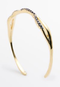 Bracciale d'oro con un design intrecciato, caratterizzato da gemme nere lungo un bordo. Texture liscia con una finitura lucida e levigata.