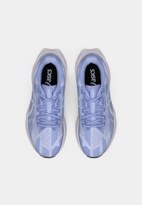 Zapatos deportivos de color púrpura claro con parte superior de punto texturizado, diseño de cordones y suela gris. Presenta una marca en la lengua y el panel lateral.