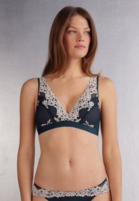 Brassière sans fil vert foncé avec un bord en dentelle, arborant un décolleté en V plongeant et une bande sans couture, accompagnée d'un slip en dentelle assorti.