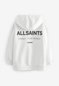Fehér kapucnis felső kenguruzsebbel, nagy fekete felirattal, amely tartalmazza az "ALLSAINTS" és "LONDON" szavakat, valamint további japán szöveget.