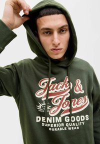 Zelená mikina s kapucí vyrobená z měkké tkaniny, s potiskem na přední straně s nápisem "Jack & Jones" ve stylizovaném červeném a bílém písmu. Kapuce se stahovací šňůrkou a žebrované manžety.