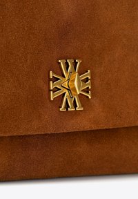 Brązowa torebka z zamszu z zapięciem w kolorze złotym w kształcie promieni słonecznych oraz wytłaczanym zdobieniem, co tworzy teksturowe wykończenie.