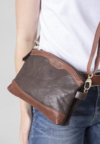 Brown leather crossbody bag with a darker brown bottom. Features a zip closure, decorative metal accents, and an adjustable strap.
