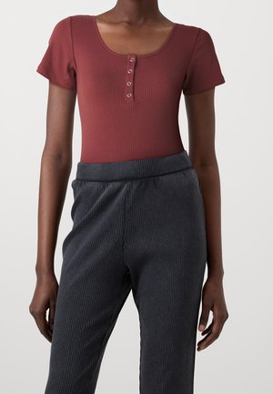 Bordowy prążkowany body z krótkimi rękawami i guzikami, zestawiony z szarymi prążkowanymi spodniami z elastycznym pasem.