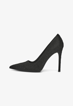 Chaussure noire à talons hauts avec un bout pointu, ornée de petites clous brillants. Texture lisse, talon aiguille fin et design de décolleté bas.