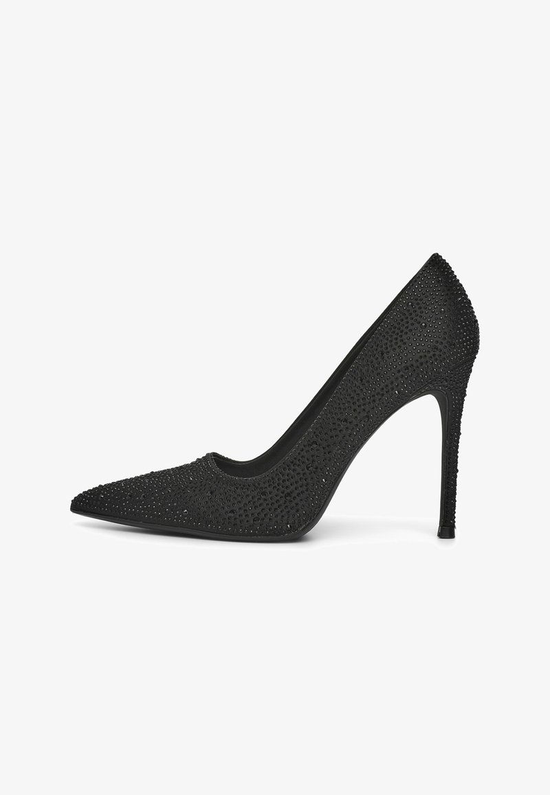 Scarpa nera con tacco alto e punta appuntita, decorata con piccole borchie lucide. Texture liscia, tacco a stiletto sottile e design con scollatura bassa.