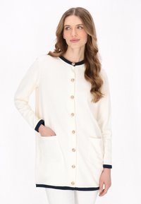 Cardigan alb cu accente bleumarin, închidere cu butoane și două buzunare frontale. Prezintă o textură moale și un guler rotund.