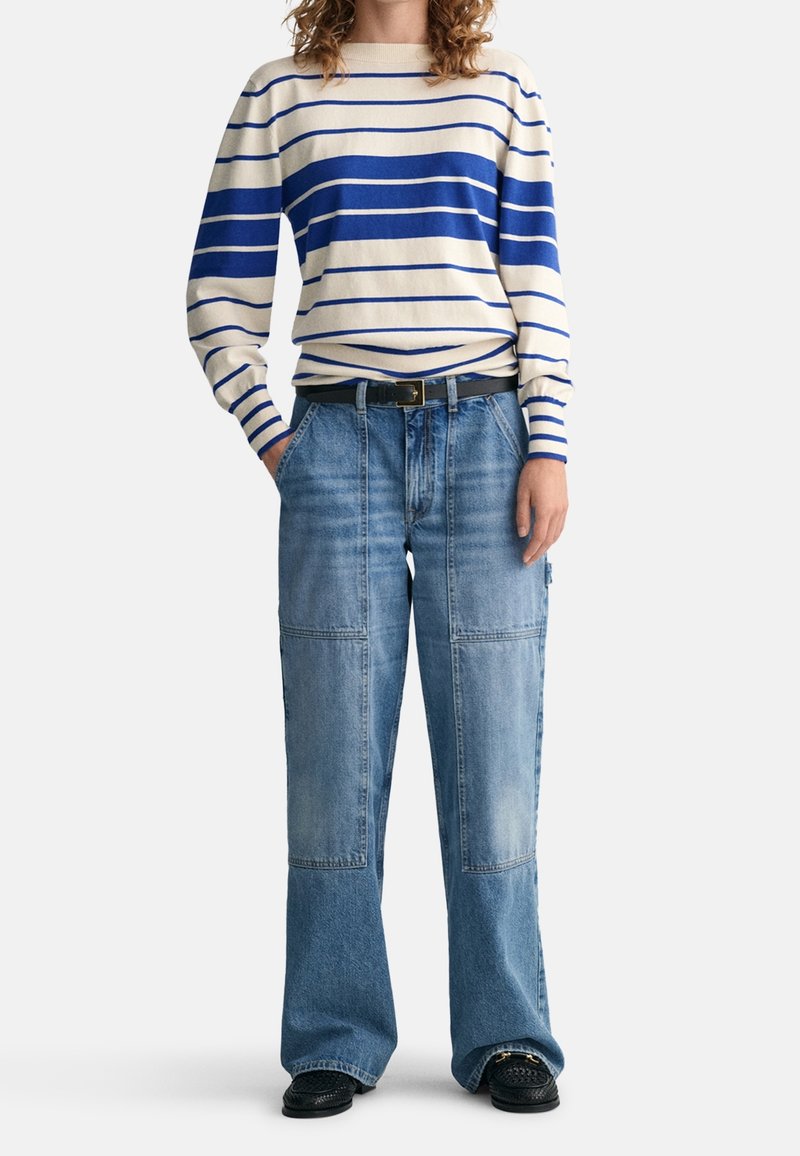 Lätt randig tröja med blå och off-white ränder, tillsammans med vida ljusblå denim cargo-byxor med fickor.