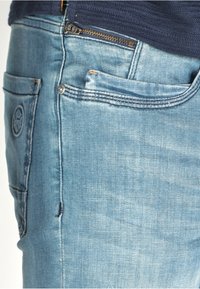 Ljusa blå denimjeans med en strukturerad passform, subtila blekningar och bakfickor med logodetaljer och mässingsknappslås.