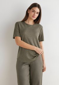 Oliven grøn t-shirt med korte ærmer i blødt stof, der har en rund halsudskæring og en afslappet pasform med en let bue nederst.