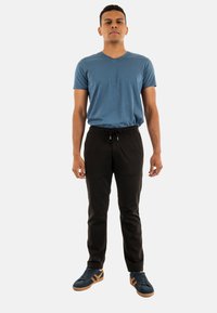 Blauwe V-hals t-shirt, zwarte broek met trekkoord en marineblauwe sneakers met oranje accenten. Soepele stof, comfortabele pasvorm, eenvoudig design.