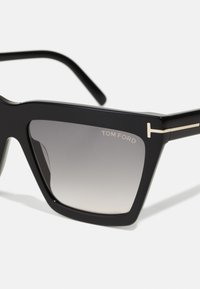 Black rectangular sunglasses with gradient lenses, a bold frame design, and subtle gold accents on the temples. Marked with "TOM FORD."