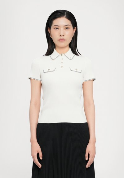 White ribbed polo shirt with short sleeves, collared neckline, decorative buttons, and contrast stitching on the edges. Two chest pockets.
