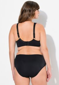 Musta bikinit-setti, jossa on yksinkertainen muotoilu, kangasrakennetta, säädettävät hihnat ja klipsilukko yläosassa. Korkeavyötäröiset alaosat.