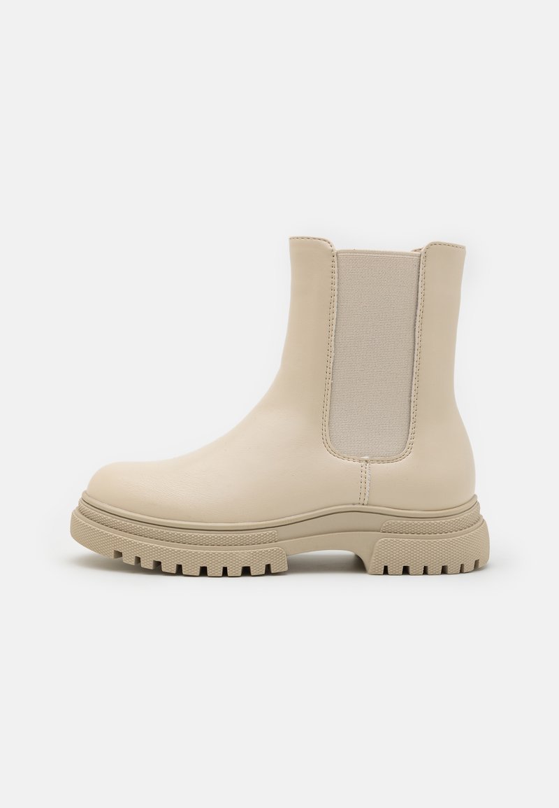 Bottines beiges en cuir lisse avec des panneaux latéraux en élastique, un bout arrondi et une semelle épaisse et robuste avec un motif de crans.