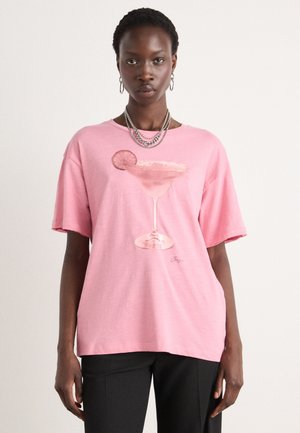 Pink cotton t-shirt featuring a graphic of a cocktail glass with a slice of lime. Relaxed fit and short sleeves. Simple design and soft texture.