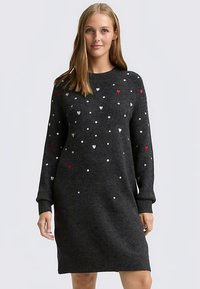 Vestito grigio lavorato a maglia con maniche lunghe, caratterizzato da motivi di cuori bianchi e rossi sparsi e polsini a coste. Lunghezza fino a metà coscia. Tessuto morbido.