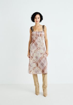 Floral-patterned, light pink midi dress with square neckline, ruffled trim, and animal print straps, paired with beige knee-high boots.