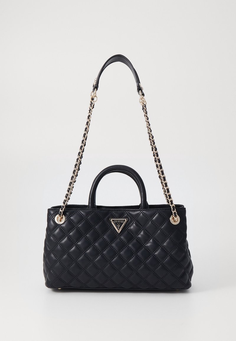 Sac à main en cuir matelassé noir avec double poignée et bandoulière chaîne dorée, orné d'une plaque logo Guess triangulaire à l'avant.
