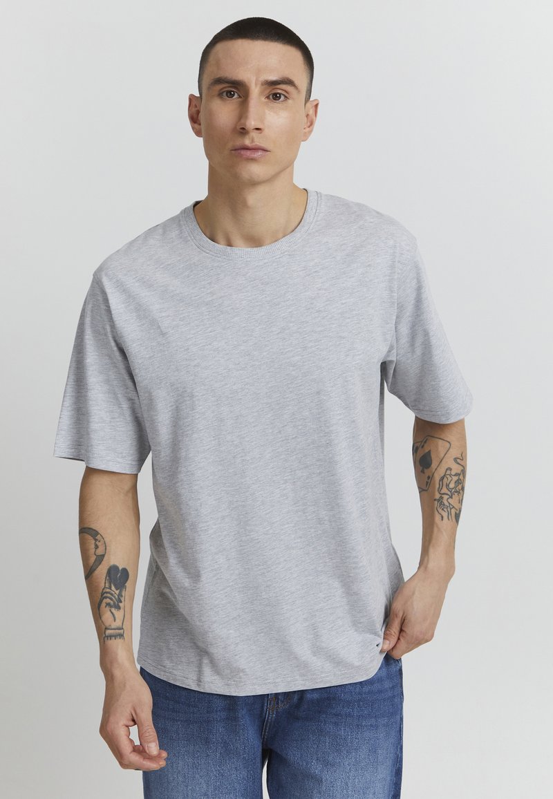 Gray short-sleeve t-shirt with a round neck, made of cotton; worn by a person with tattoos on their forearm. Simple and casual design.