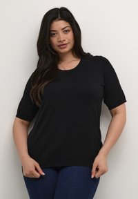Top negro de manga corta con cuello redondo. Está hecho de una tela suave y ligera. Corte relajado, con un ligero estiramiento.