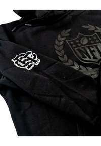 Schwarzer Hoodie mit einem strukturierten NFL-Logo und Lorbeerdesign. Verfügt über eine bestickte weiße Grafik am Ärmel. Weicher Stoff, lässige Passform.