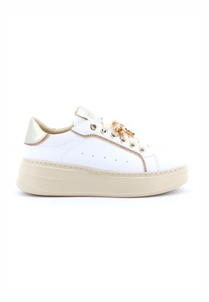 Sneaker bianca bassa con suola platform beige, occhielli dorati, rifiniture dorate e decorazioni colorate a forma di gioielli sui lacci.