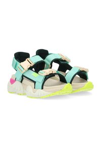 Sandali sportivi con cinturini in tessuto verde menta, fibbie in plastica beige, accenti neri e una suola strutturata color crema con dettagli giallo neon.