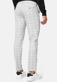 Szare spodnie w kratę wykonane z teksturowanej tkaniny, charakteryzujące się eleganckim krojem o dopasowanym fasonie, tylnymi kieszeniami oraz paskiem z zapięciem na guziki.