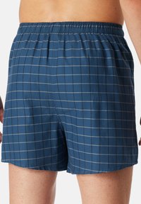 Boxer shorts a quadri blu navy con una texture morbida, vita elastica e un motivo a reticolo grigio chiaro a contrasto.