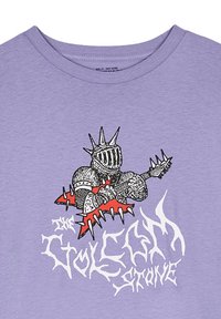 Camiseta de algodón de color púrpura claro con un gráfico negro y rojo de un caballero armado tocando la guitarra, con texto estilizado abajo.