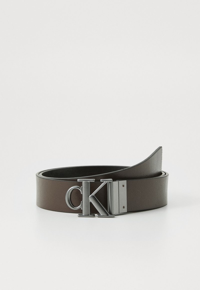 Cinto de pele castanha com uma fivela retangular de metal prateado e o logótipo "CK", textura suave e um design elegante.