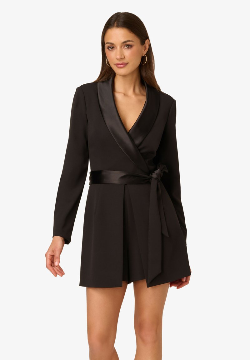 Robe portefeuille noire avec des manches longues, col en satin et une ceinture à nouer à la taille. Présente une texture lisse et une jupe courte.