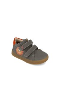 Zapato de cuero gris con acentos en naranja y diseño de león, con dos correas de Velcro, puntera redondeada y suela de goma.